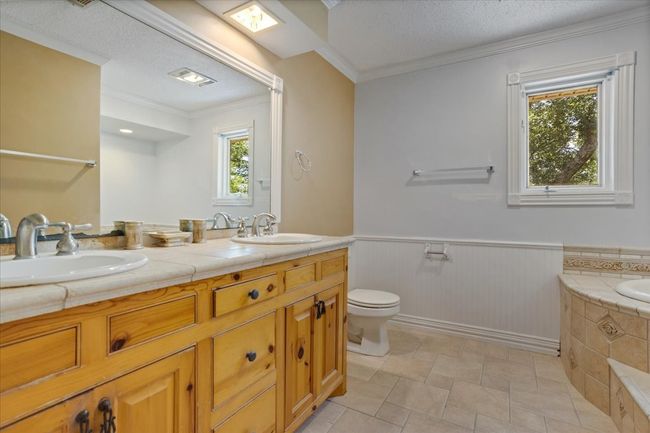 Full bathroom with double vanity, a wainscoted wall, a garden tub, healthy amount of natural light, and crown molding | Image 19
