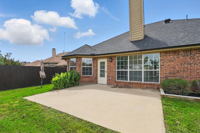 Back of house featuring brick siding, a patio, a chimney, and a shingled roof | Image 32