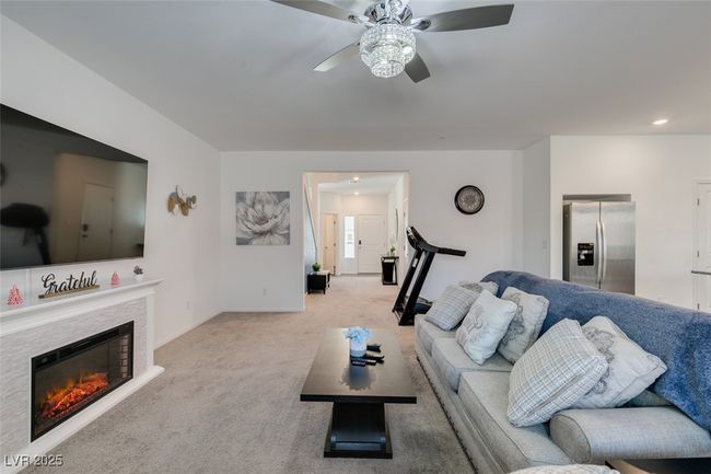 Carpeted living area with a ceiling fan and a glass covered fireplace | Image 30