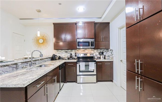 Kitchen featuring pendant lighting, sink, light tile patterned floors, appliances with stainless steel finishes, and tasteful backsplash | Image 13