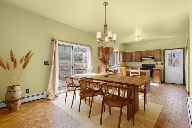 Virtually staged dining area off kitchen. Glass sliding doors to back deck. Open flow into living room. | Image 11