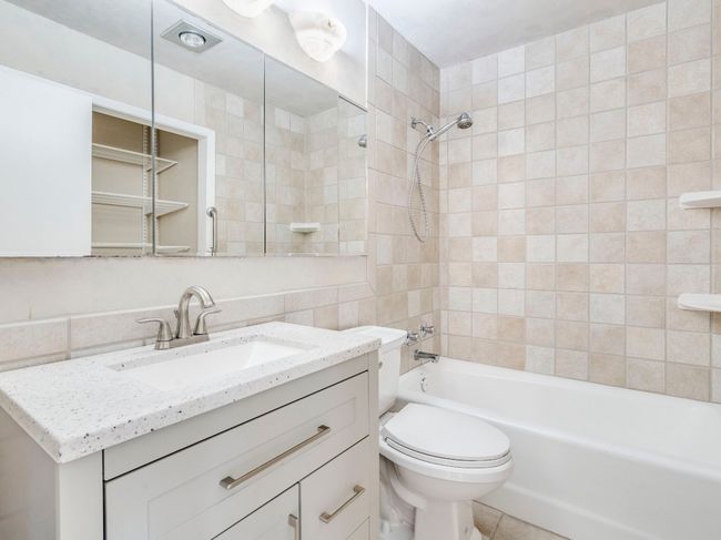 Full bath featuring shower combination, toilet, vanity, and tile walls | Image 13
