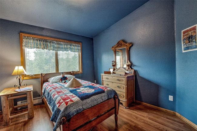 Bedroom featuring wood finished floors, lofted ceiling, baseboard heating, and a textured wall | Image 29