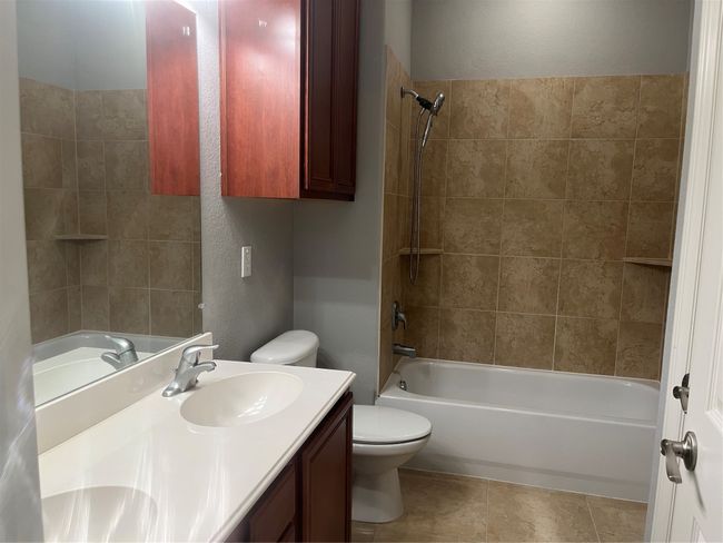 Full bathroom featuring double vanity, shower combination, and a textured wall | Image 14