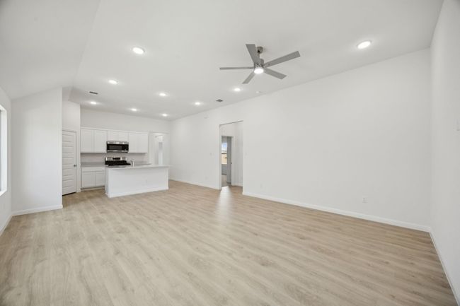 Unfurnished living room featuring a ceiling fan, light wood-style flooring, recessed lighting, and lofted ceiling | Image 14