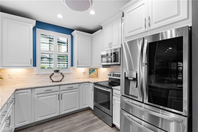 Kitchen with stainless steel appliances, white cabinetry, tasteful backsplash, light wood-style flooring, and recessed lighting | Image 8