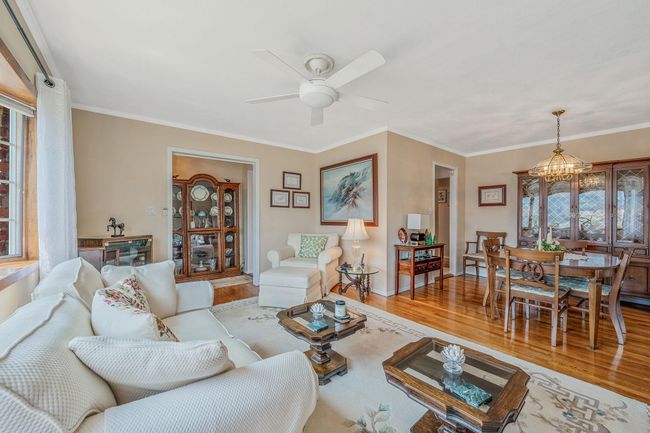 Living area featuring wood finished floors, a chandelier, a ceiling fan, and crown molding | Image 6
