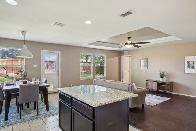 Kitchen with a tray ceiling, a center island, pendant lighting, visible vents, and a ceiling fan | Image 13