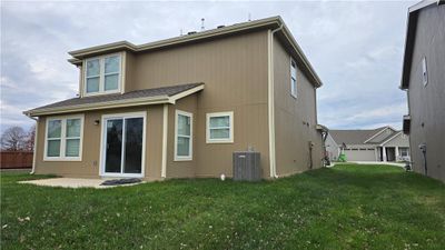 Back of house with a garage, central AC, and a yard | Image 2