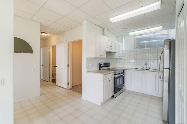 Kitchen featuring stainless steel appliances, under cabinet range hood, a sink, light floors, and white cabinets | Image 47