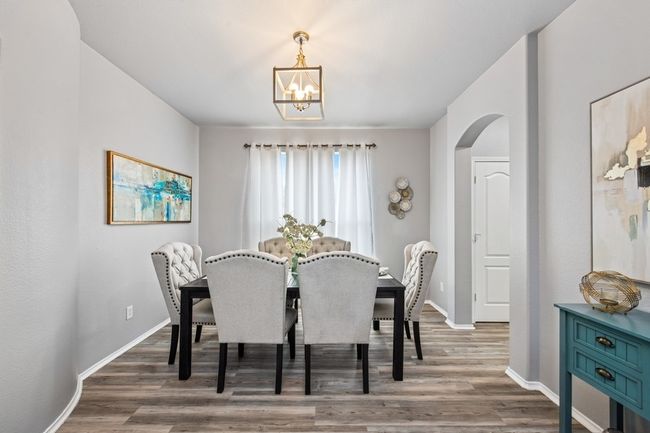 Dining room with baseboards, arched walkways, a notable chandelier, and wood finished floors | Image 11