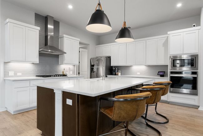 This luxurious kitchen boasts a massive center island/breakfast bar, quartz countertops, and a built-in microwave over oven. | Image 12