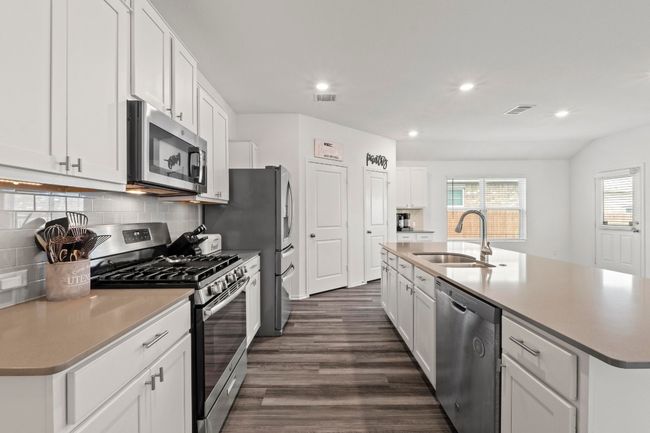 A chef's kitchen with ceramic subway tile backsplash and upgraded stainless steel appliances. | Image 7