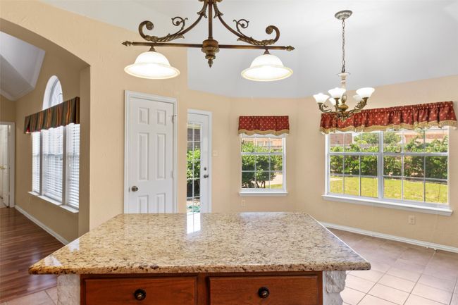 Kitchen featuring healthy amount of natural light, light tile patterned floors, a chandelier, light stone countertops, and vaulted ceiling | Image 30