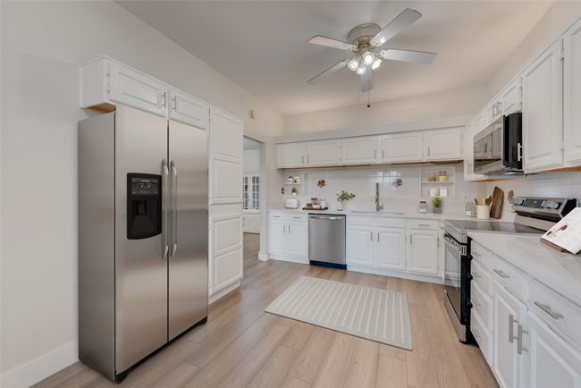 Kitchen with appliances with stainless steel finishes, backsplash, a ceiling fan, and light countertops | Image 8