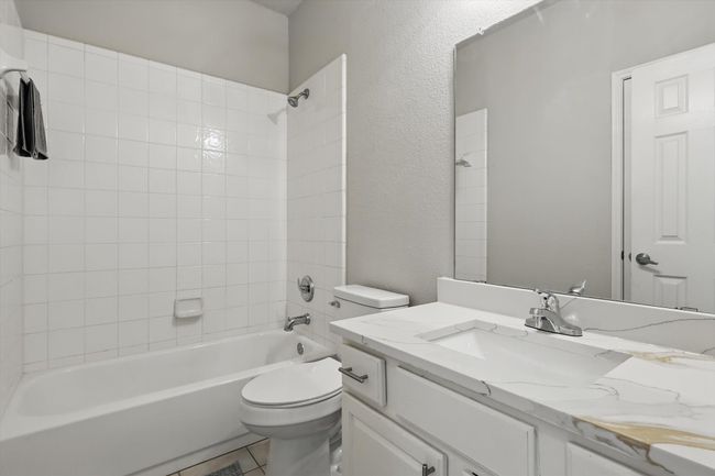 Full bath with vanity, shower / tub combination, a textured wall, and tile patterned flooring | Image 23