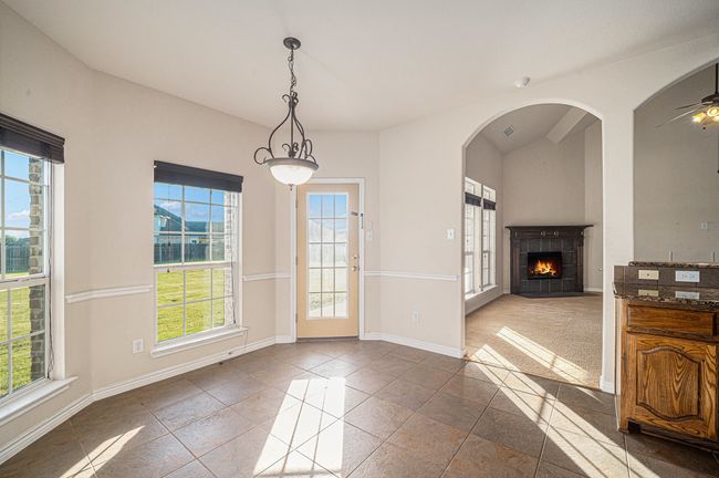 Unfurnished dining area with a tile fireplace, baseboards, a ceiling fan, and arched walkways | Image 11