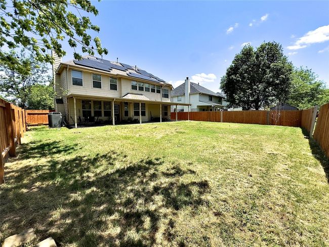 Rear view of property featuring central AC unit, roof mounted solar panels, and a chimney | Image 35