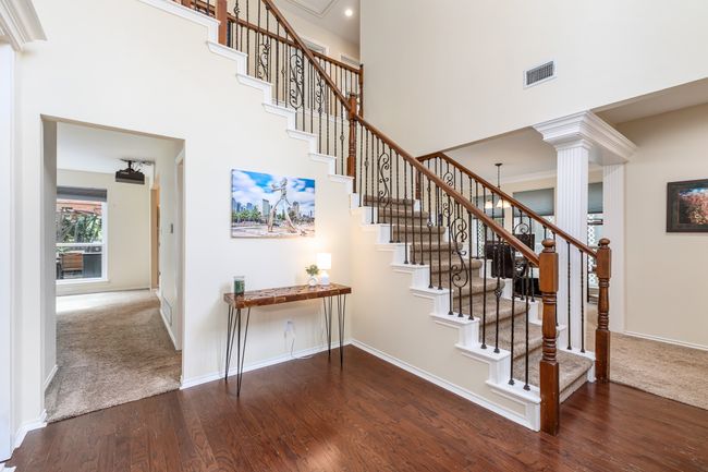 Staircase featuring a high ceiling, wood finished floors, decorative columns, carpet flooring, and recessed lighting | Image 4