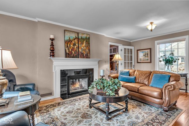 living area featuring ornamental molding, wood finished floors, and a tile fireplace | Image 8