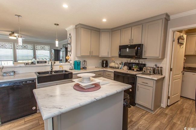 Kitchen featuring crown molding, a sink, black appliances, light wood finished floors, and gray cabinets | Image 6