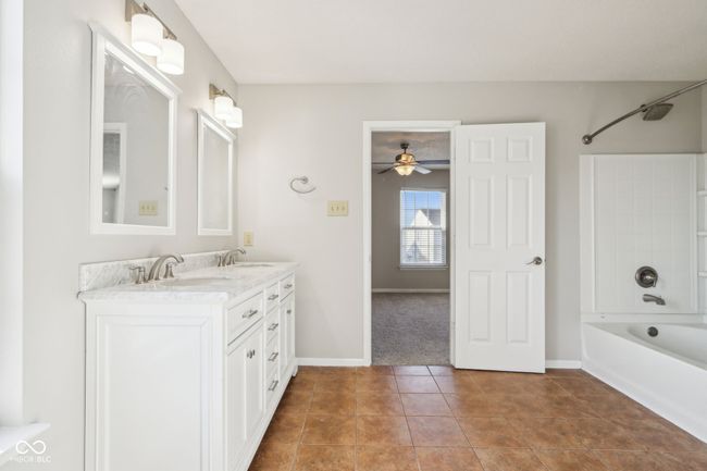 bathroom with double vanity, shower / tub combination, a ceiling fan, baseboards, and tile patterned flooring | Image 44