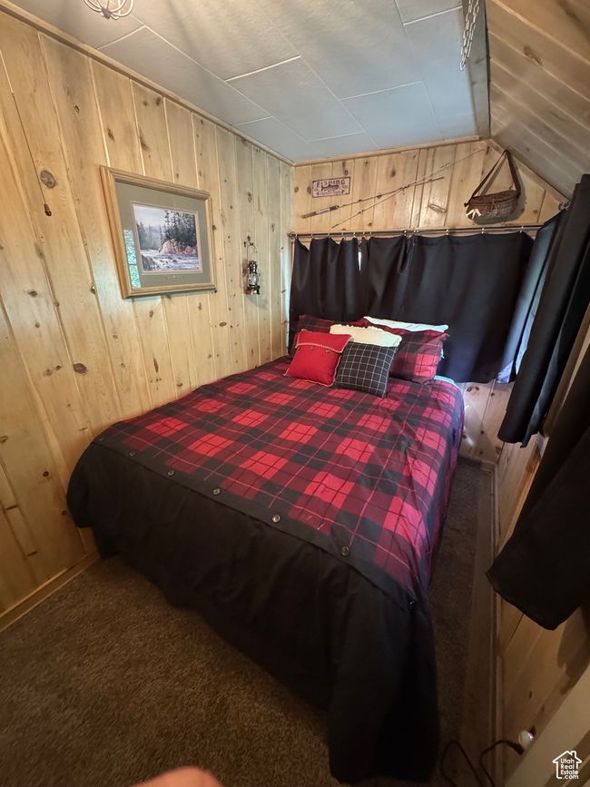 Bedroom featuring wood walls, lofted ceiling, and carpet | Image 8