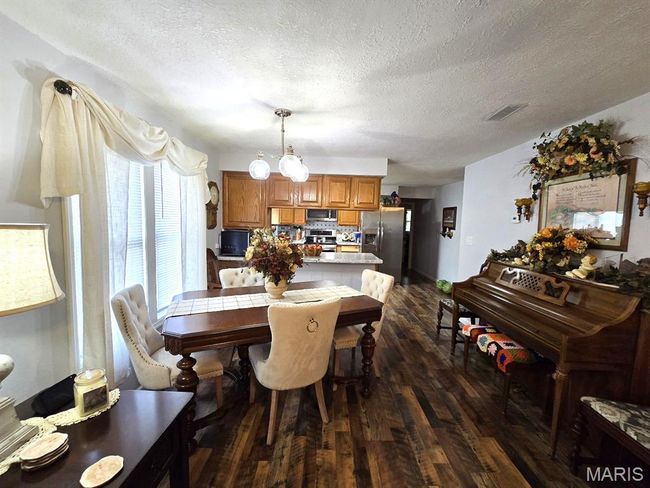 Dining space featuring dark wood-type flooring and a textured ceiling | Image 6
