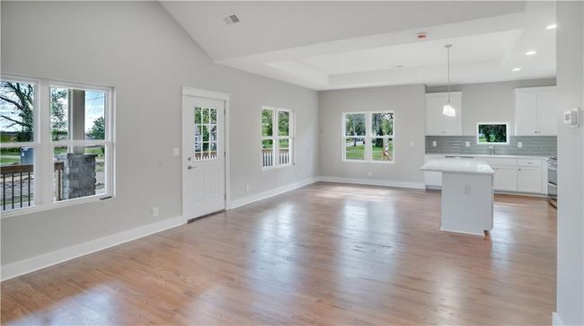 Kitchen with light countertops, white cabinets, a kitchen island, tasteful backsplash, and open floor plan | Image 5