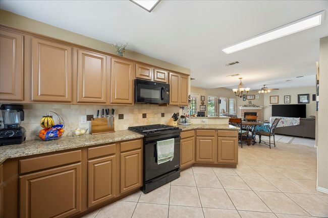 Kitchen featuring black appliances, a chandelier, decorative backsplash, and a peninsula | Image 13
