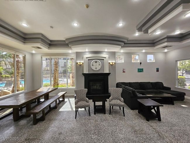 Living area featuring a raised ceiling, a glass covered fireplace, visible vents, and carpet | Image 11