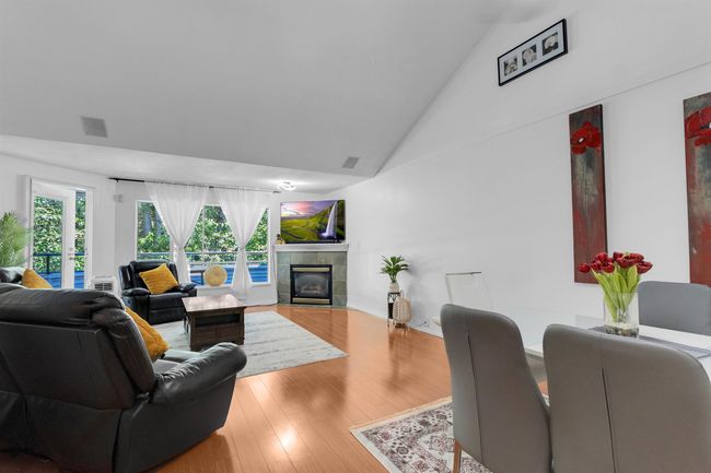 Living room featuring a tile fireplace, wood finished floors, healthy amount of natural light, and high vaulted ceiling | Image 4