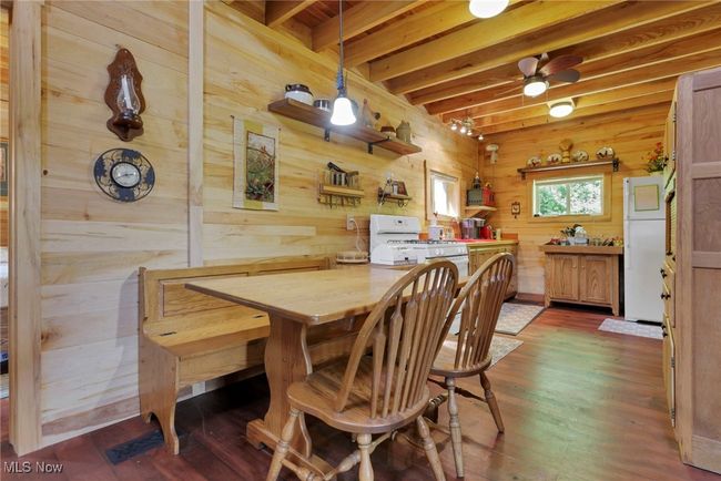 Dining space featuring wood walls, dark wood-type flooring, and beam ceiling | Image 15