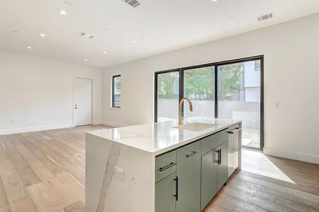 Kitchen featuring light wood-style floors, recessed lighting, an island with sink, light stone counters, and open floor plan | Image 16