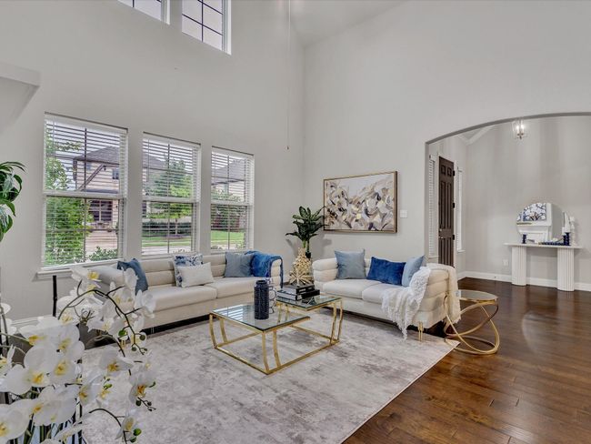 Living room featuring a high ceiling, arched walkways, hardwood / wood-style floors, and healthy amount of natural light | Image 5