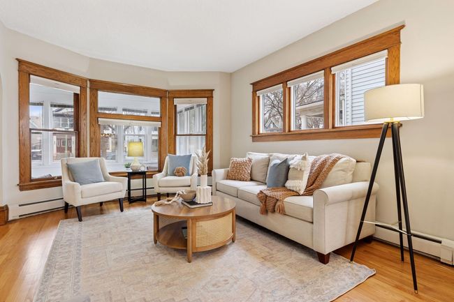 The living room is bathed in natural light from expanses of sunny windows. | Image 9