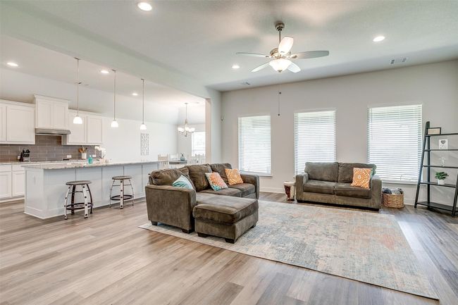 Living room with ceiling fan, light wood finished floors, recessed lighting, a chandelier, and baseboards | Image 7