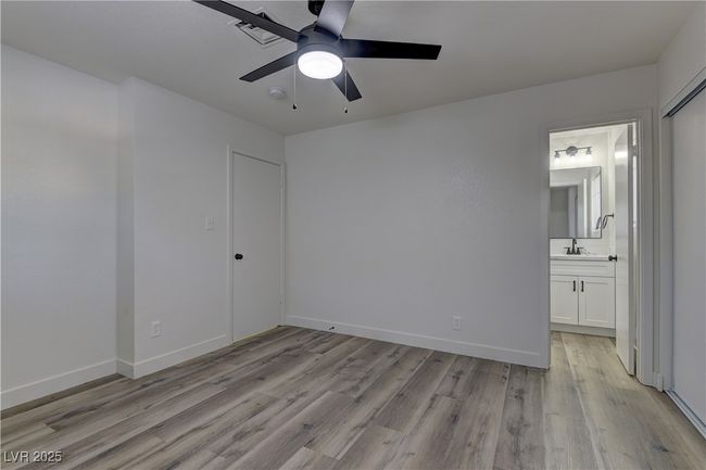 Unfurnished bedroom with light wood-type flooring, connected bathroom, baseboards, and ceiling fan | Image 19