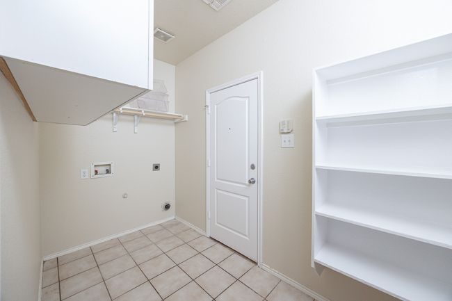Laundry area featuring hookup for an electric dryer, washer hookup, light tile patterned floors, and hookup for a gas dryer | Image 16