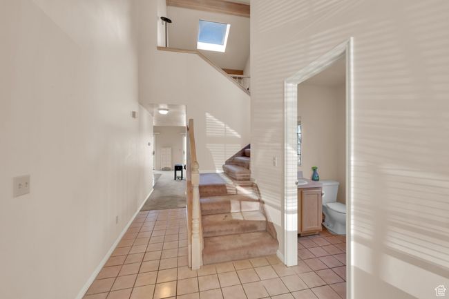 Staircase with baseboards, a towering ceiling, tile patterned flooring, and a skylight | Image 10