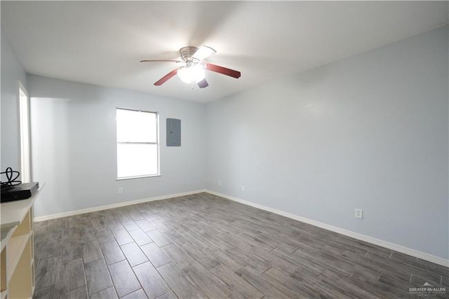 Unfurnished room featuring ceiling fan, electric panel, and dark wood-style floors | Image 11