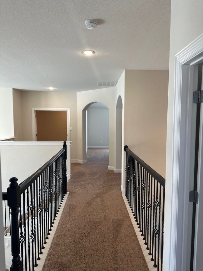 Hall with carpet, arched walkways, visible vents, a textured ceiling, and an upstairs landing | Image 23