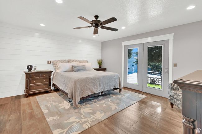Bedroom featuring light hardwood / wood-style floors, a textured ceiling, wood walls, access to outside, and ceiling fan | Image 19