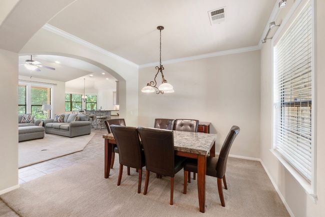 Dining area with arched walkways, a ceiling fan, crown molding, light colored carpet, and a chandelier | Image 4