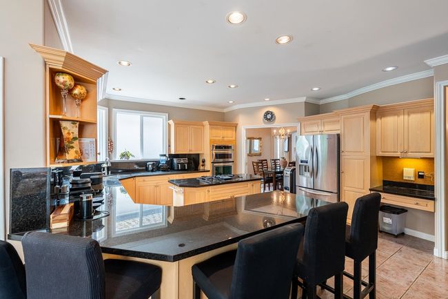 Kitchen featuring light brown cabinets, open shelves, appliances with stainless steel finishes, light tile patterned floors, and ornamental molding | Image 15
