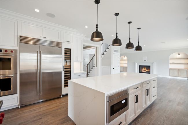 Kitchen featuring built in appliances, wood finished floors, white cabinets, pendant lighting, and open floor plan | Image 5