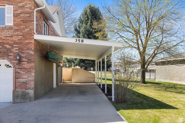 View of parking / parking lot with a carport, fence, and concrete driveway | Image 41