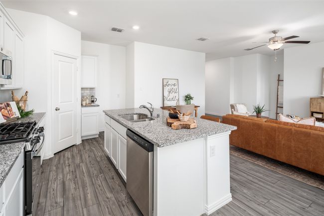 Kitchen featuring a sink, stainless steel appliances, open floor plan, wood finished floors, and a kitchen island with sink | Image 9