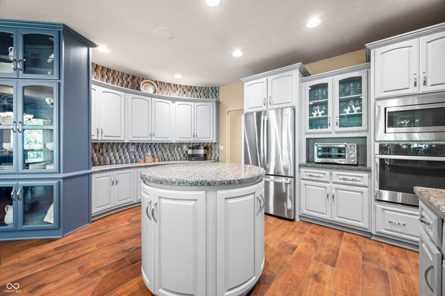 kitchen featuring a toaster, stainless steel appliances, glass insert cabinets, and dark wood-style flooring | Image 32