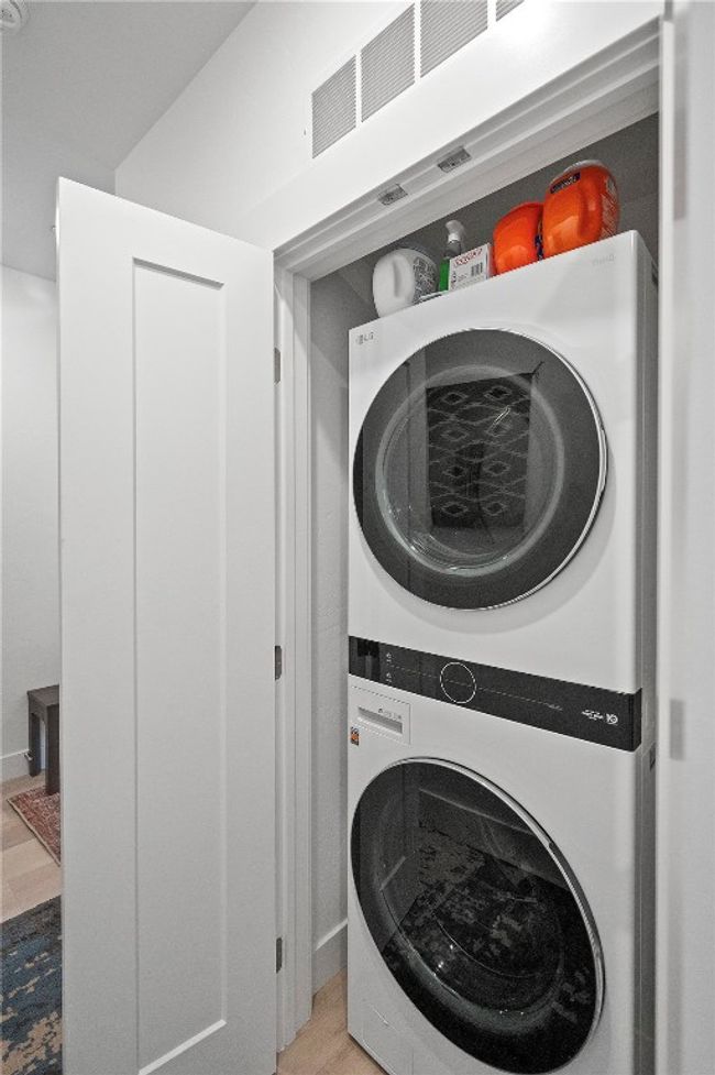 Laundry area featuring stacked washer and dryer and light wood-type flooring | Image 23